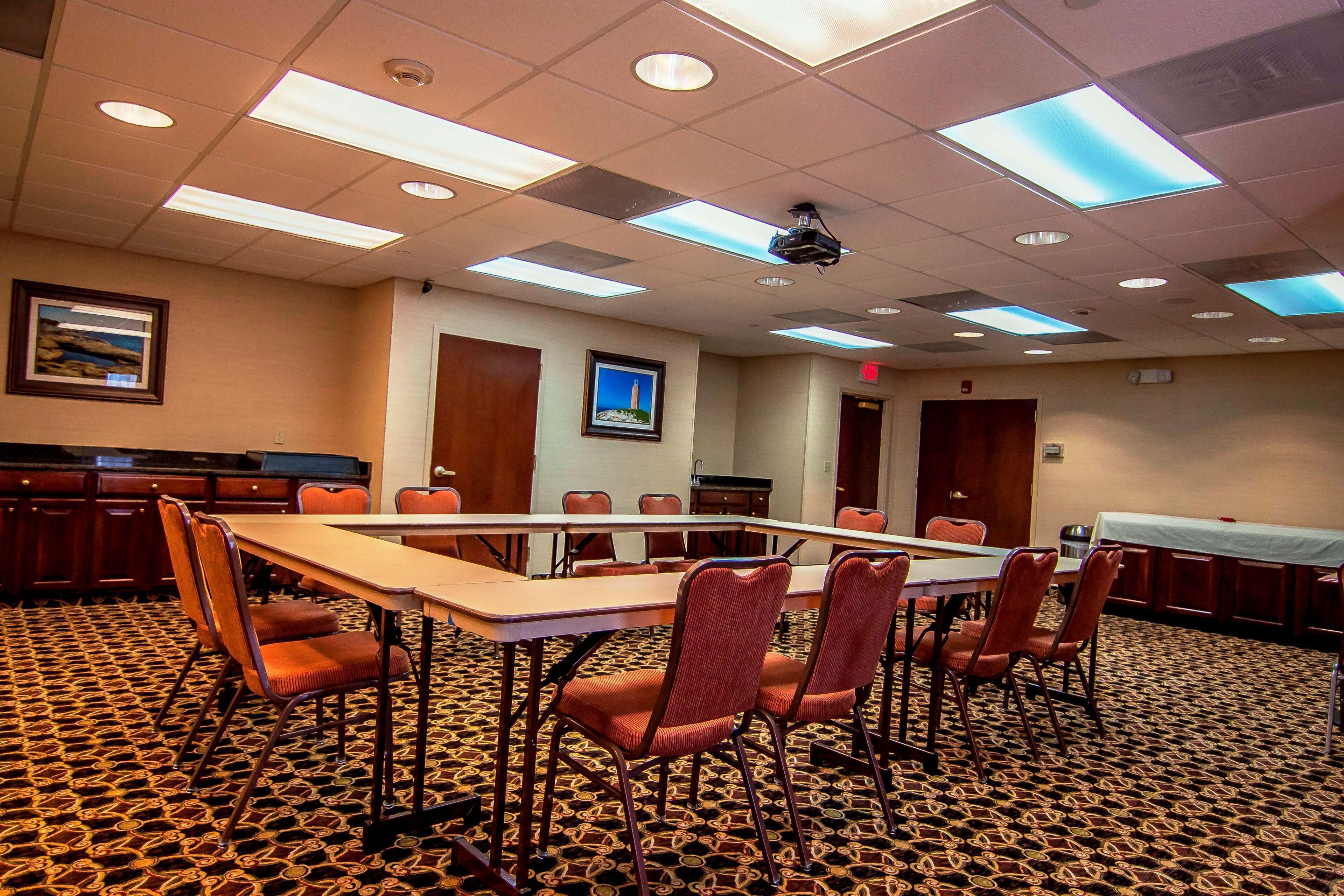 A conference room with a long table, multiple chairs, and a patterned carpet.