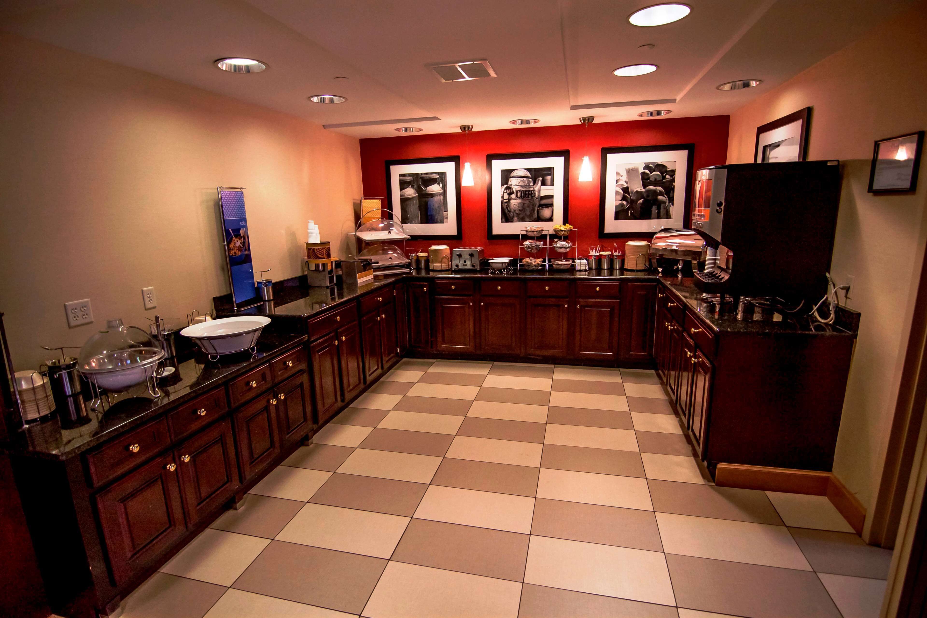 A kitchen with a checkered floor, wooden cabinets, and a coffee station.
