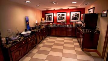 A kitchen with a checkered floor, wooden cabinets, and a coffee station.