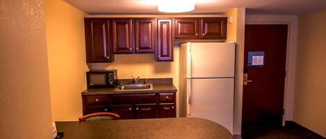 A compact kitchen with wooden cabinets, a white refrigerator, and a small countertop.