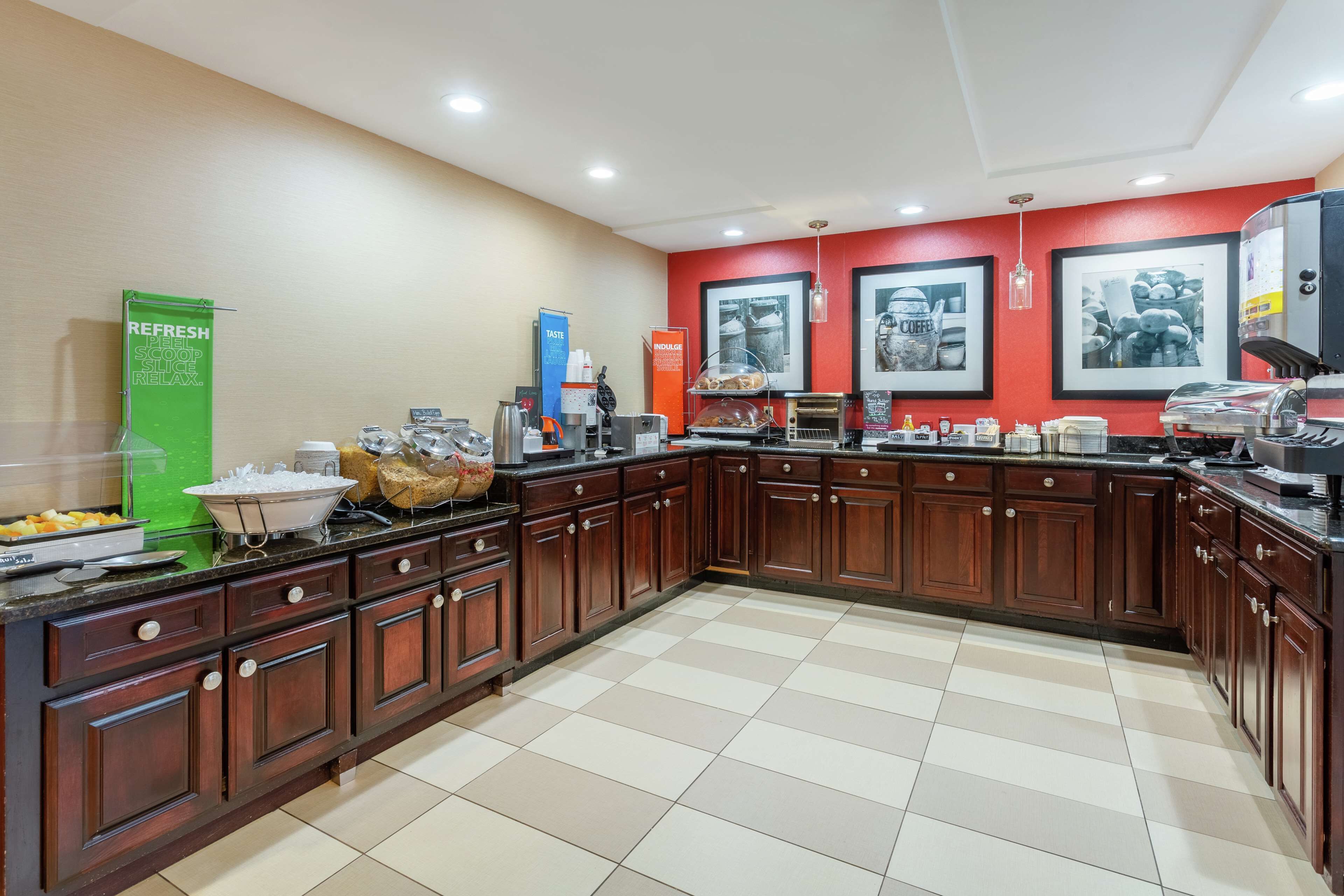 A spacious kitchen with wooden cabinets, a large island, and a red accent wall.