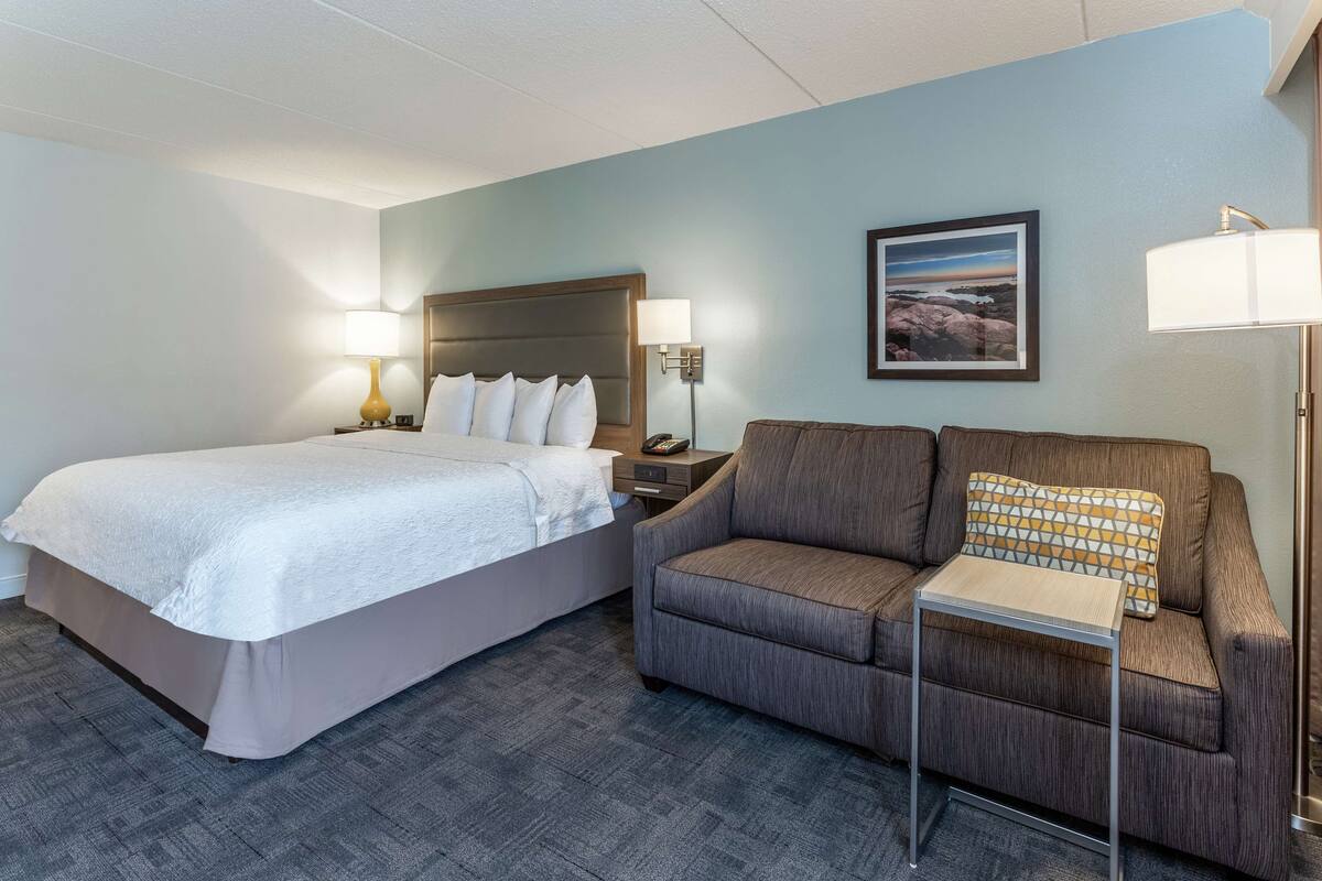 Una habitación de hotel con una cama, un sofá, una mesita y una mesita de noche.