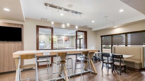 A modern kitchen with a bar area, bar stools, and a seating area with a bench and chairs. - Sleep Inn Clovis (Clovis)