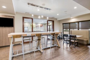 A modern kitchen with a bar area, bar stools, and a seating area with a bench and chairs.