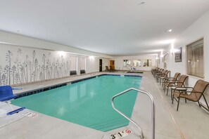 A swimming pool with a tiled border, a blue chair, and a row of brown chairs along the poolside.