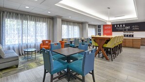 Un hall d’hôtel moderne avec un espace salon, un bar et un panneau publicitaire pour des gaufres.