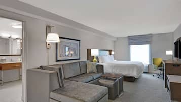 Una habitación de hotel moderna con sofá, cama, escritorio y una silla.