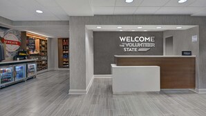Un espace d’accueil avec une pancarte indiquant « Bienvenue aux bénévoles », un mini-bar et une enseigne « Hilton ».