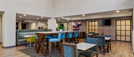 A spacious indoor area with multiple seating arrangements, including tables and chairs, and a reception desk in the background.
