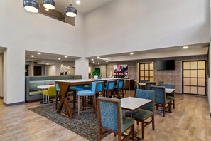 A spacious indoor area with multiple seating arrangements, including tables and chairs, and a reception desk in the background. - Hampton Inn Jacksonville/Ponte Vedra Beach-Mayo Clinic Area (Jacksonville Beach)