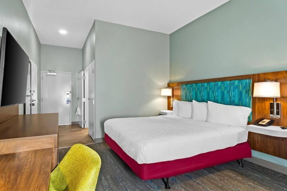 Una habitación de hotel con cama, mesitas de noche, escritorio, silla y televisor.