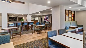 Un moderno vestíbulo de hotel con zona de bar, asientos y mostrador de recepción.