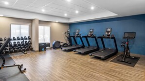 Un gimnasio con cintas de correr, elípticas y mancuernas.