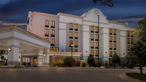 Un hotel grande de varios pisos con una entrada destacada, una zona cubierta con iluminación y un diseño en forma de estrella en la fachada.