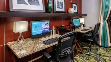 Habitación de hotel con dos escritorios, cada uno con una computadora, una lámpara y una silla. En la pared, encima de los escritorios, hay cuadros enmarcados.