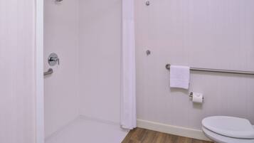 A bathroom with a shower, toilet, and a towel rack.