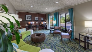 A hotel lobby with a patterned carpet, seating area with couches and chairs, a small table, and a desk with computers. - Hampton Inn Eugene (Eugene)