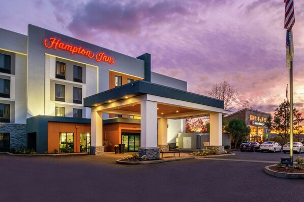 A Hampton Inn hotel with a modern exterior, a covered entrance, and a parking area.