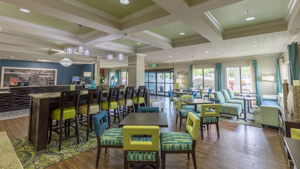 A spacious dining area with high ceilings, modern lighting, and comfortable seating. - Hampton Inn Eugene (Eugene)