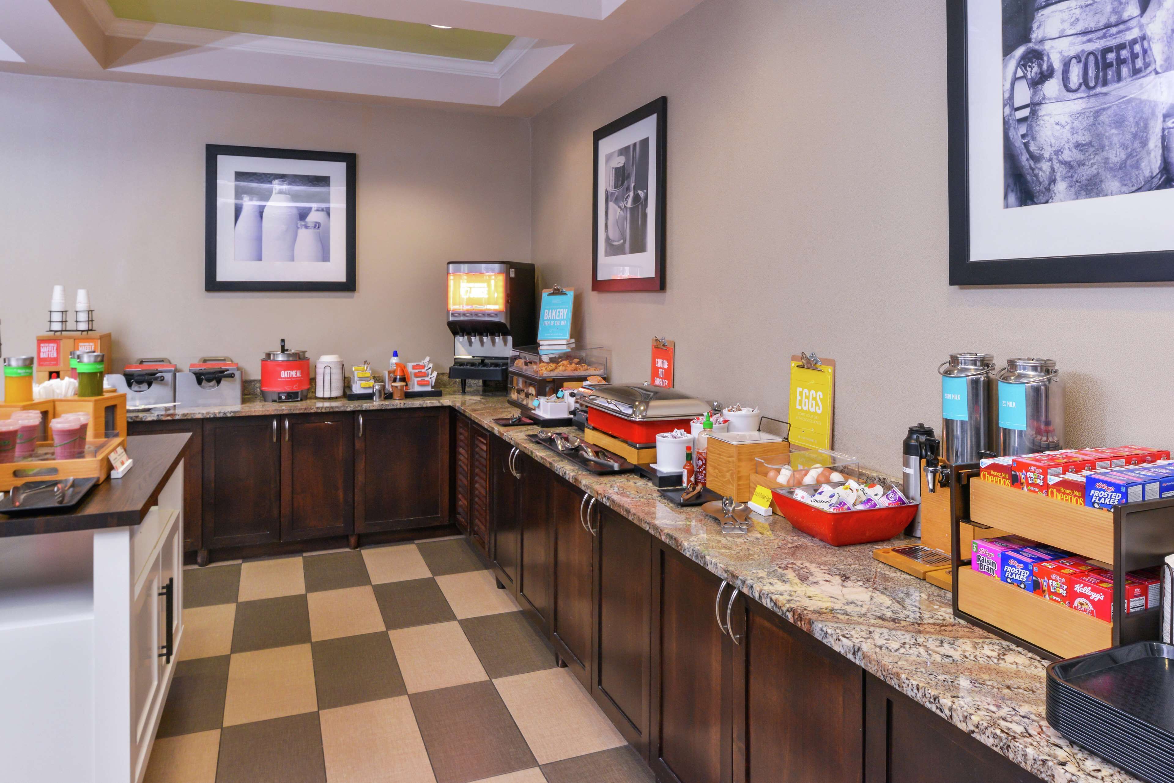 A hotel kitchen with a checkered floor, a coffee machine, and various food items on the counter.