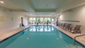 A pool area with a clear pool, chairs, and a lifeguard stand.