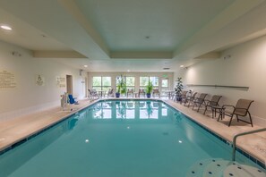 A pool area with a clear pool, chairs, and a lifeguard stand.