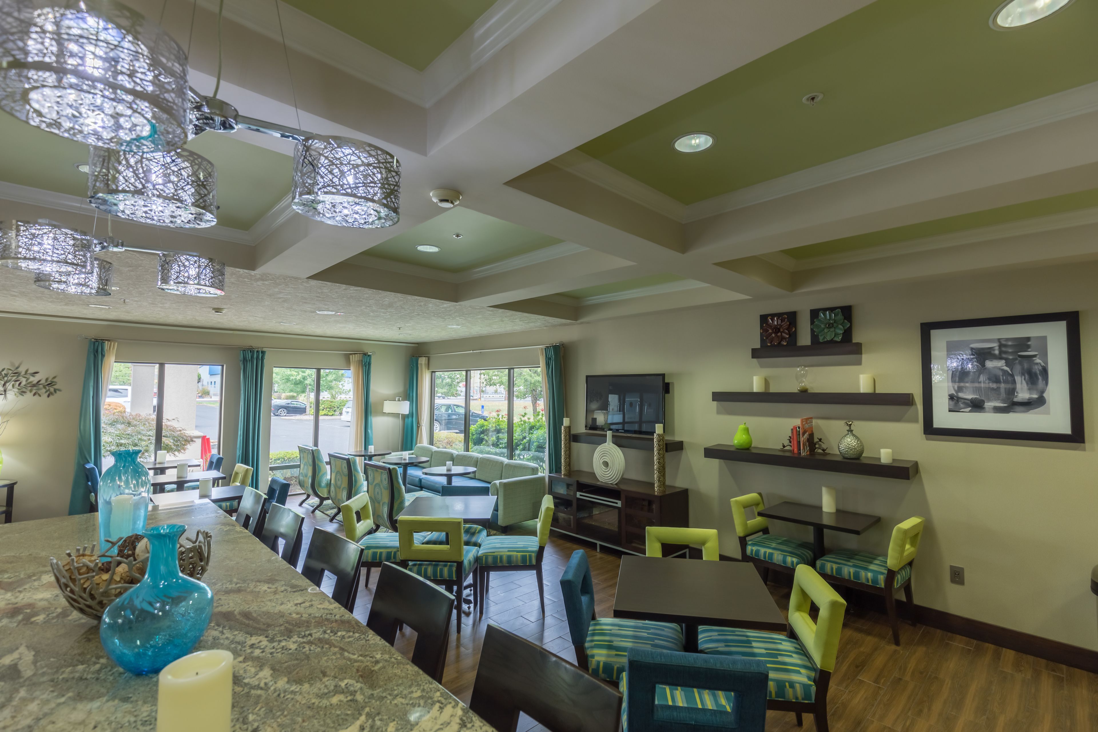 A spacious dining area with high ceilings, modern chandeliers, and comfortable seating.