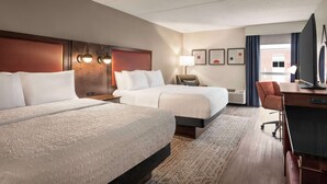 A hotel room with two beds, a desk, a chair, a lamp, and artwork on the wall. - Hampton Inn Columbia-Downtown Historic District (Columbia)