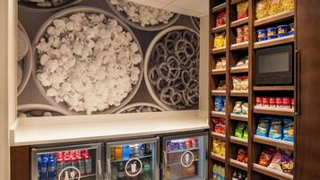Ein Imbissstand mit Getränkeautomaten und Regalen voller Snacks und Getränke.
