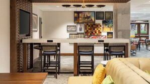 A modern bar area with a high ceiling, bar stools, and a central bar counter. - Hampton Inn Columbia-Downtown Historic District (Columbia)