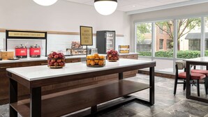 A modern breakfast area with a long counter, two hanging pendant lights, and a view of the outdoors through large windows. - Hampton Inn Columbia-Downtown Historic District (Columbia)