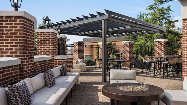 An outdoor patio area with brick walls, a covered seating area, and a fire pit. - Hampton Inn Columbia-Downtown Historic District (Columbia)