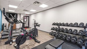 Ein Fitnessstudio mit Laufbändern, Hanteln und einer Trainingsbank.