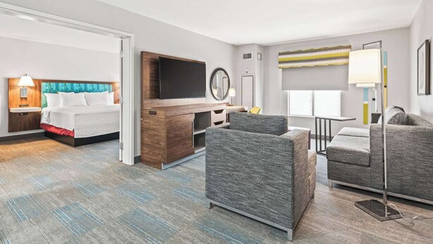 Ein Hotelzimmer mit einem Bett, einem Schreibtisch, einem Fernseher und zwei Sesseln.