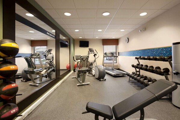 A gym with exercise equipment, a bench, and a wall-mounted mirror.