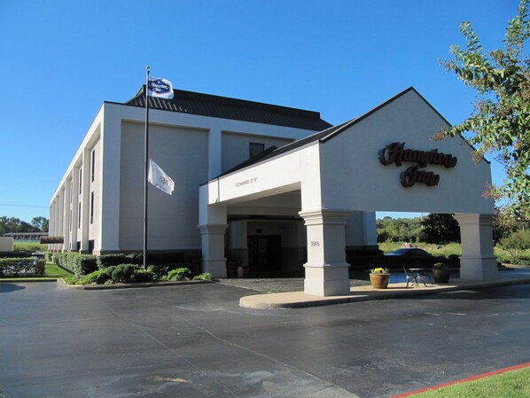 A Hampton Inn with a clear entrance, a sign indicating a clearance of 13'-0", and a flagpole with a flag.