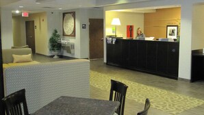 Un hall de hotel con mostrador de recepción, zona de estar y una mesa con sillas.