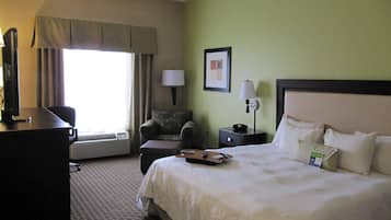 A hotel room with a bed, a desk, a chair, a lamp, and a picture on the wall.