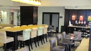 Vestíbulo de hotel con área de bar, asientos y piso estampado.