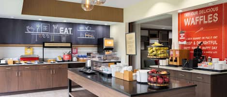 Un moderno comedor con un menú en una pizarra, una estación de café y una exhibición de gofres.