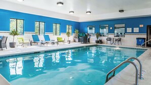 An indoor swimming pool with blue walls, multiple lounge chairs, and potted plants. - Hampton Inn Ottawa (Starved Rock Area) (Ottawa)