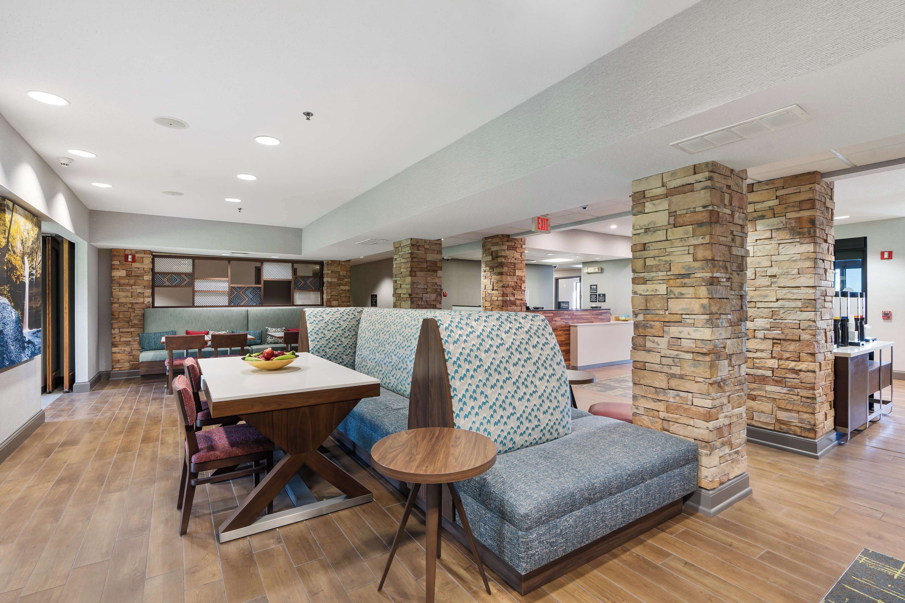 Una hall d'albergo moderna con area ristorazione, posti a sedere e reception.