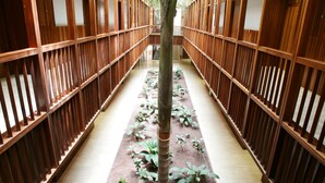 Un couloir aux murs lambrés et orné d’une plante au centre.