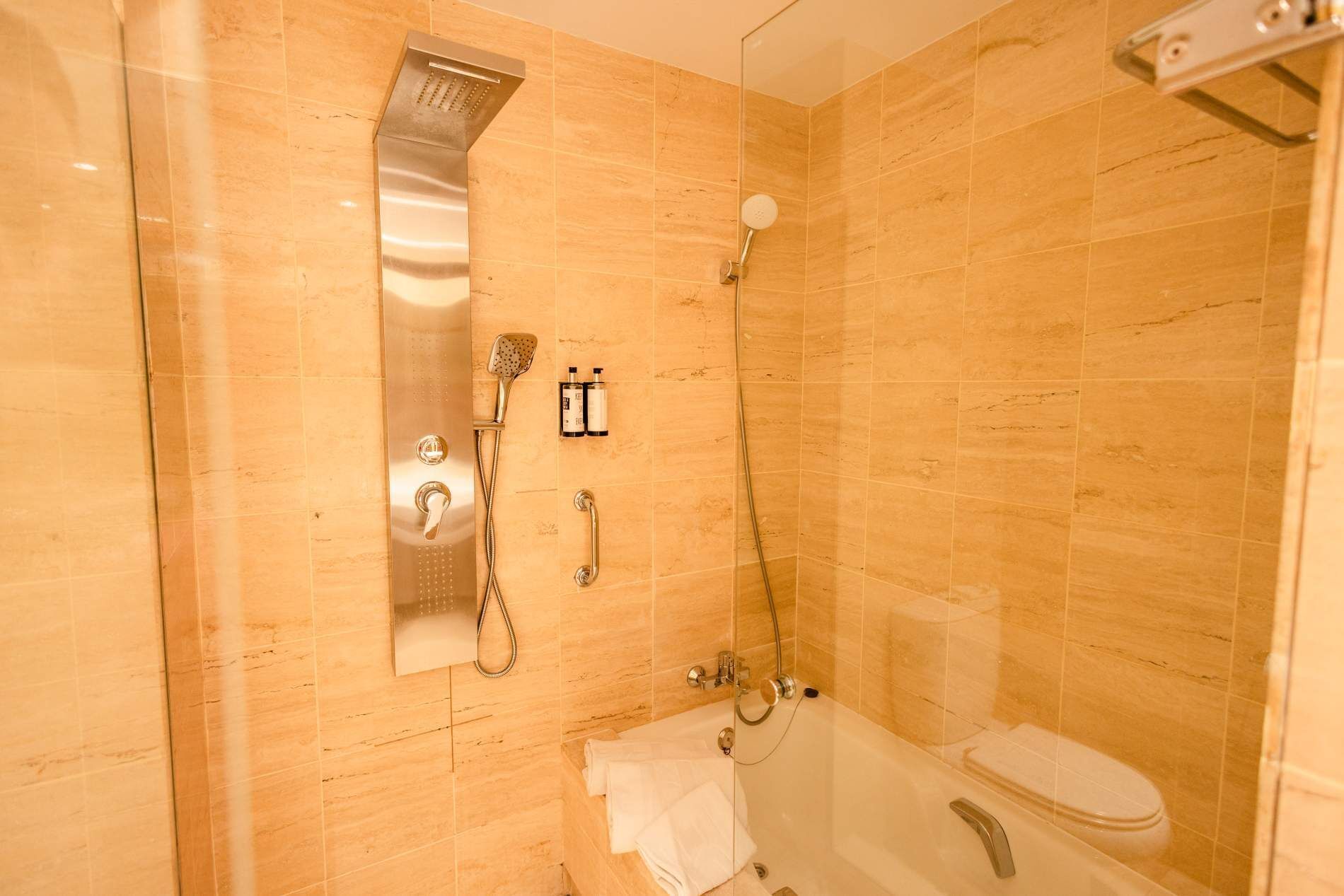 Een badkamer met een douche met glazen wand, een toilet en een handdoekhouder.