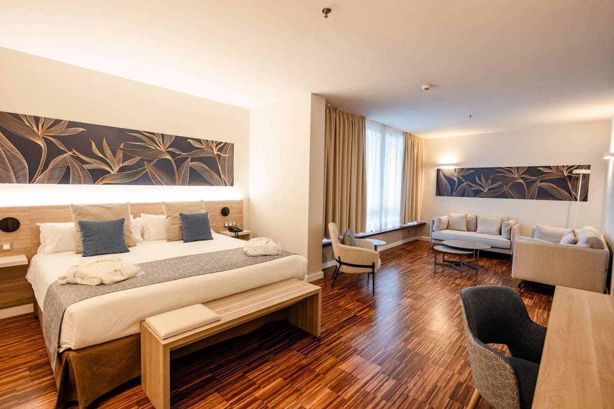 Una habitación de hotel con una cama, un sofá, un escritorio y una silla.