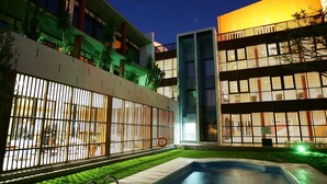 Un hôtel moderne doté d’une piscine, d’un espace extérieur aménagé et d’une façade bien éclairée.