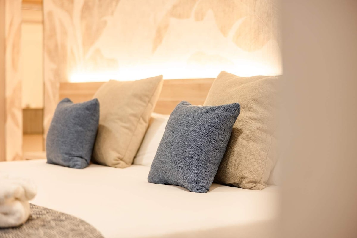 Una cama con almohadas y una colcha.