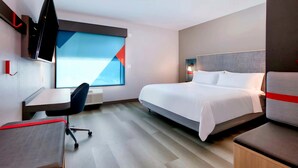 Habitación de hotel con cama, escritorio, silla, televisor y ventana con vistas.