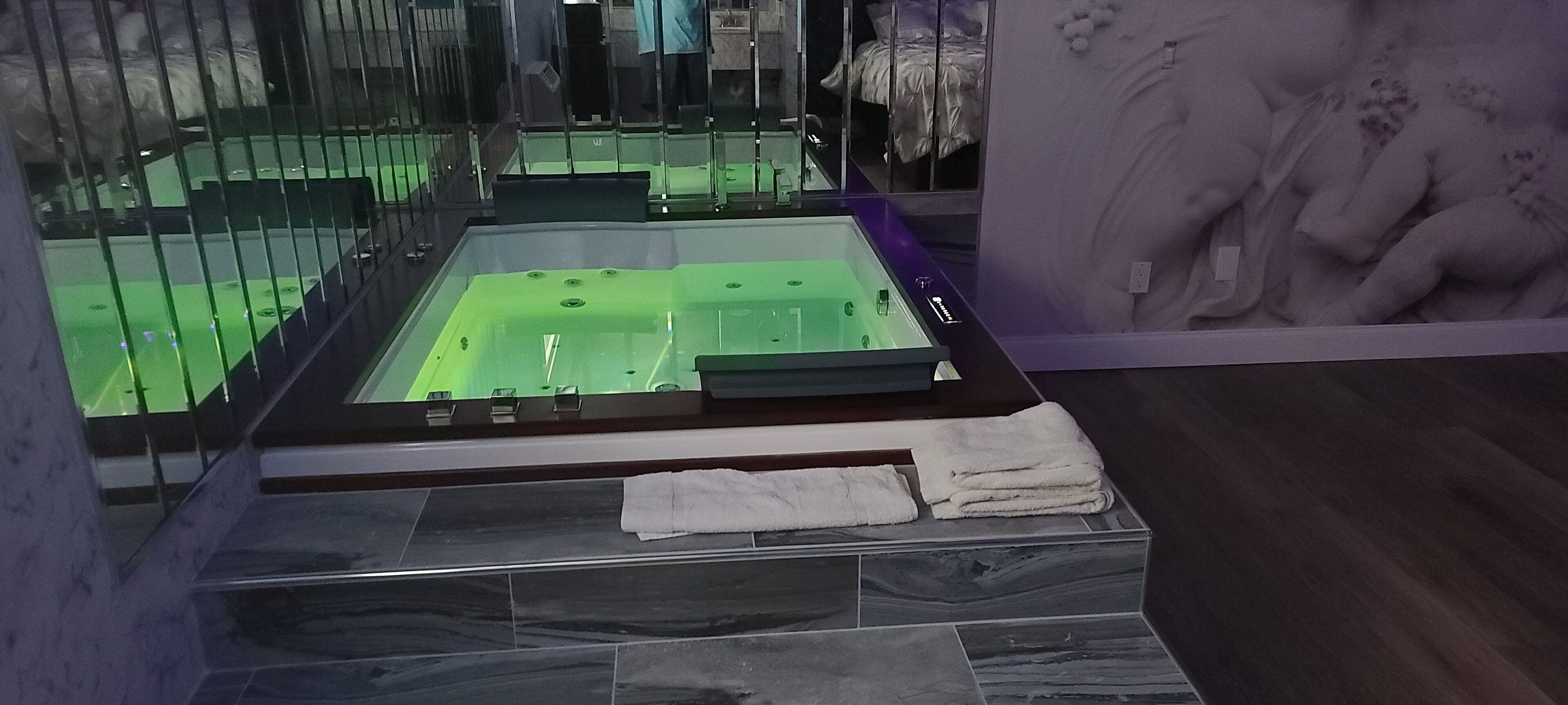 Una spa con una grande vasca da bagno, un box doccia in vetro e un pavimento in marmo.