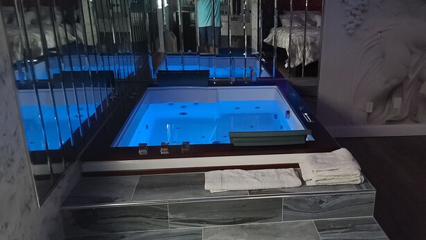 Un baño moderno con una bañera grande, cabina de cristal y suelo de mármol.